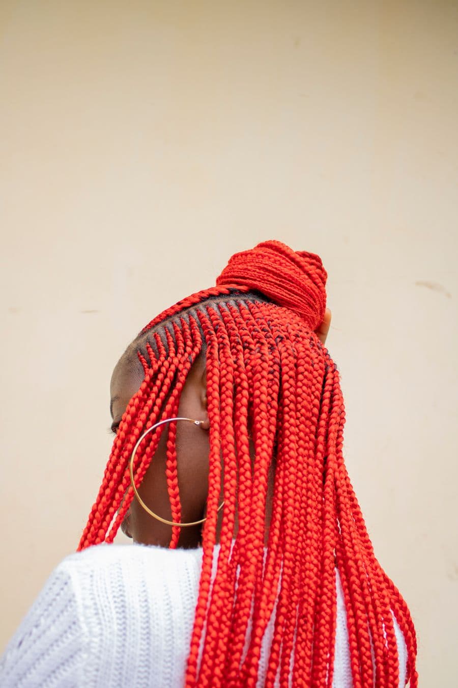 Red braids gathered in a headwrap, back view